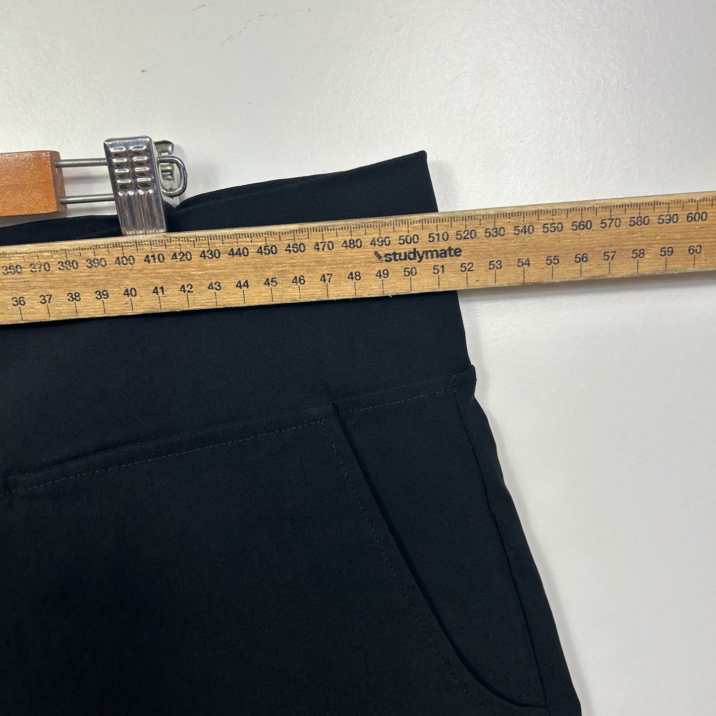 Black pants waistband detail with measuring tape