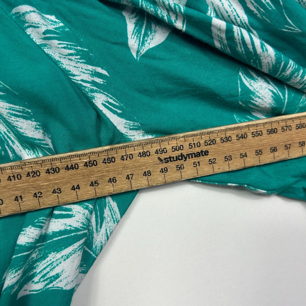 Teal fabric with white leaf pattern detail view with measuring tape