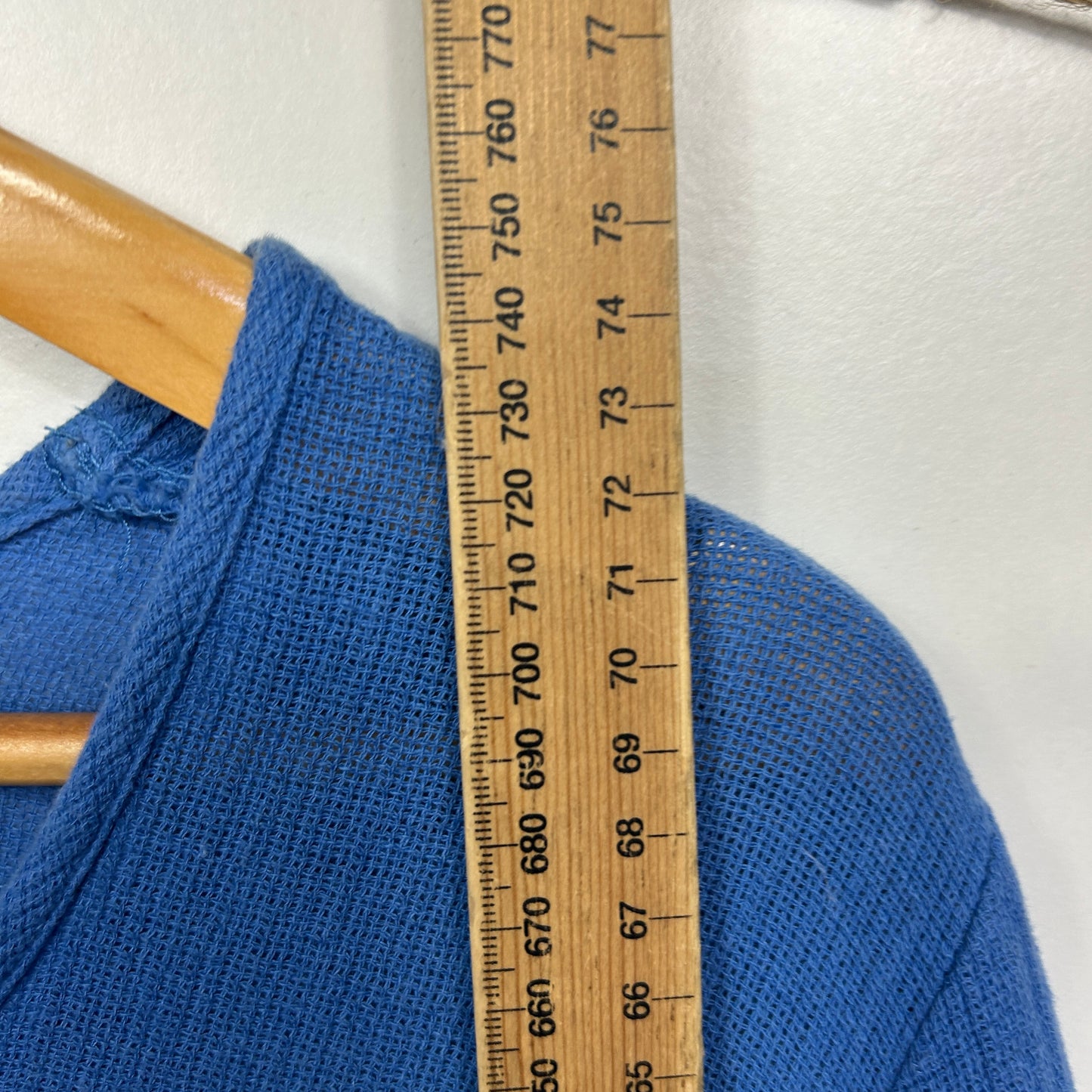 Blue knit sweater detail view with measuring tape