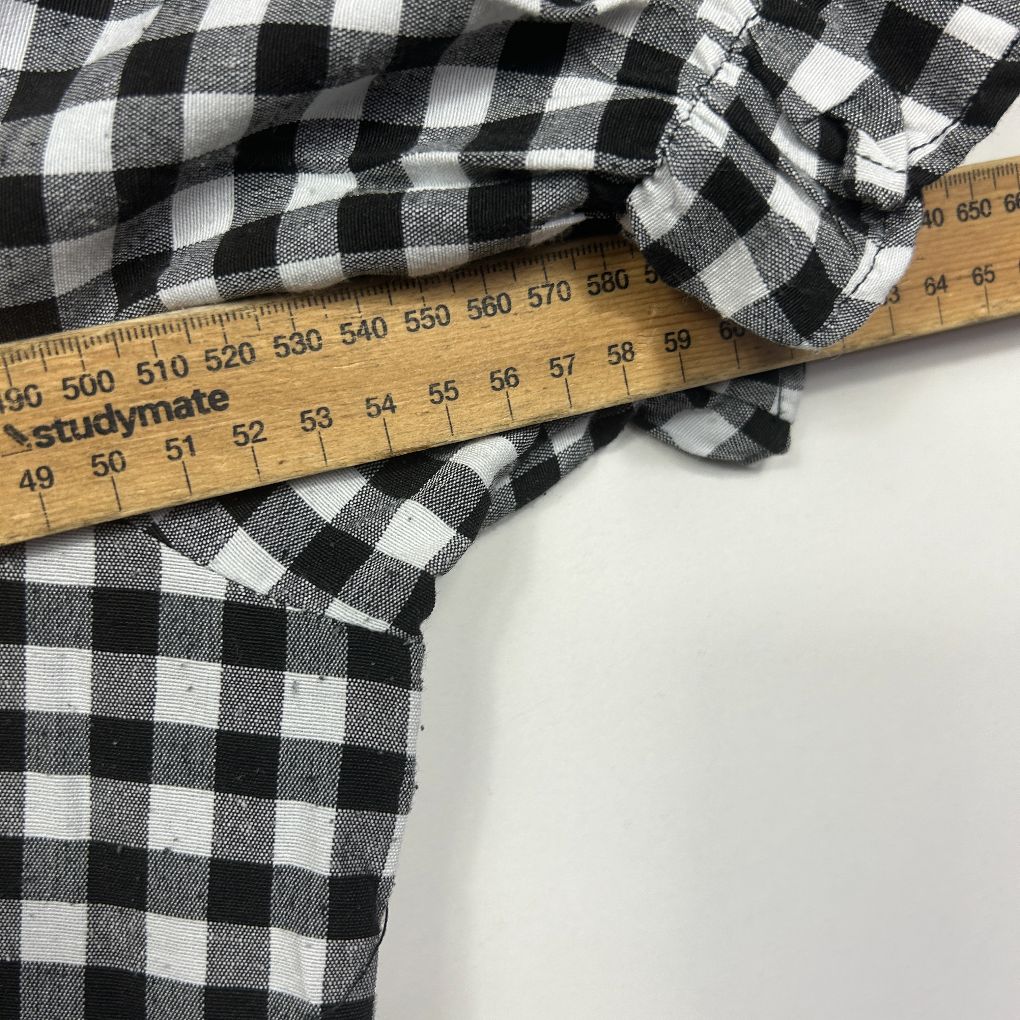 Black and white gingham check shirt detail view with measuring tape