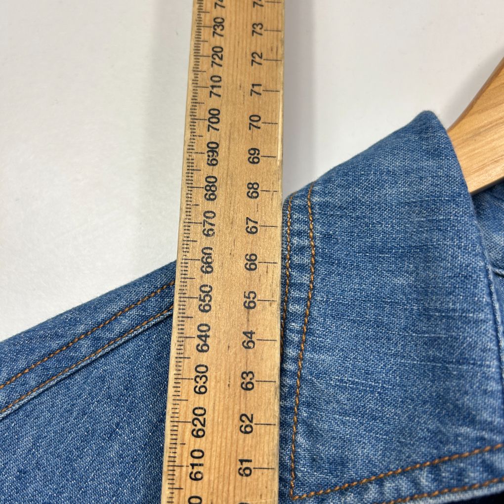 Blue denim jeans waistband detail view with measuring tape