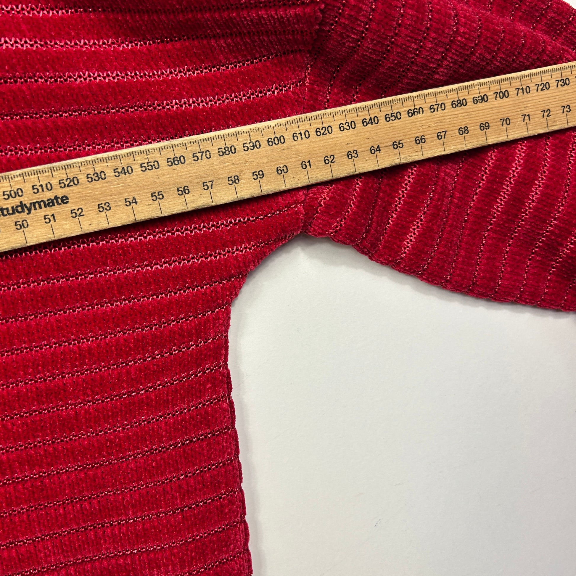 Red ribbed knit fabric detail view with measuring tape