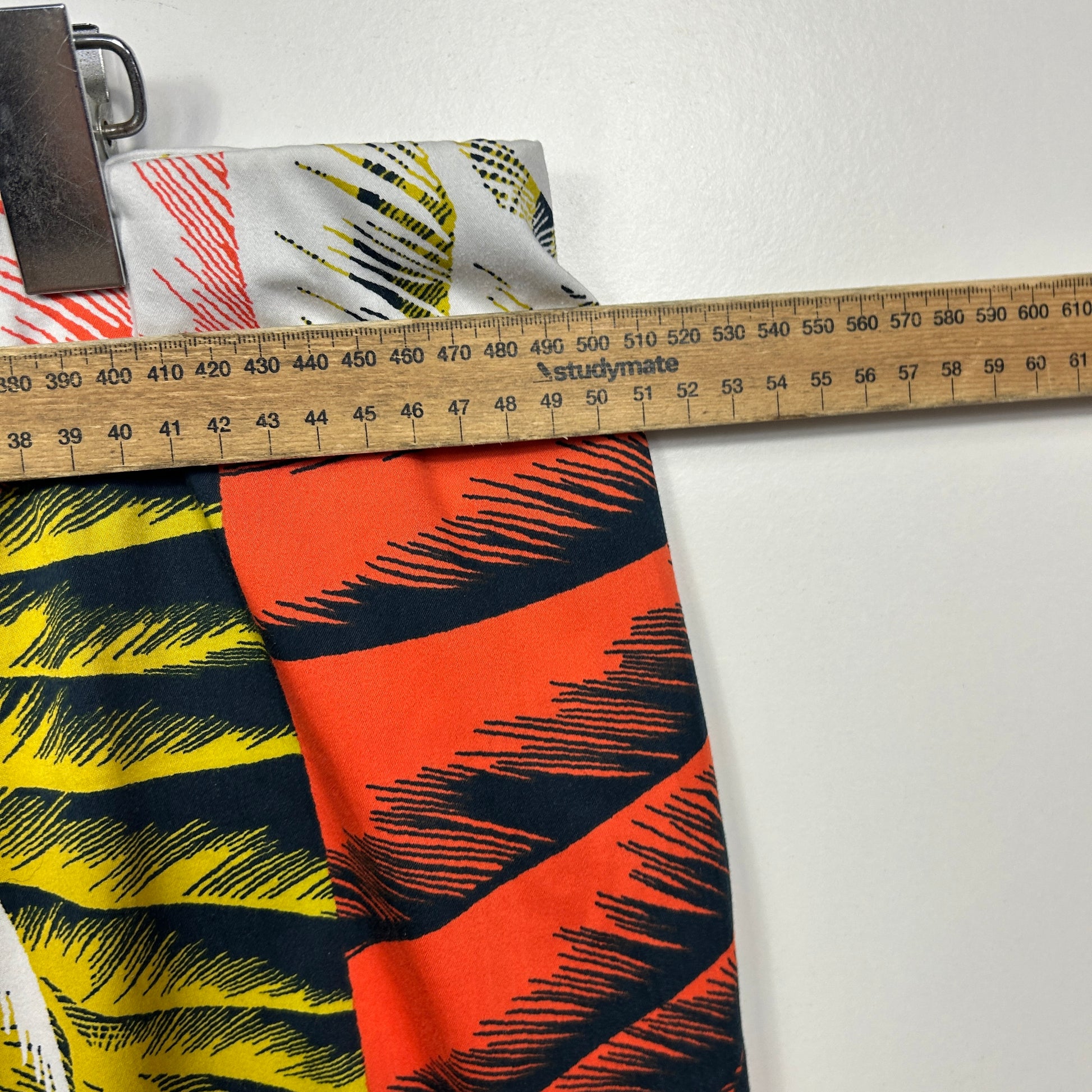 Orange and black graphic print fabric detail view with measuring tape