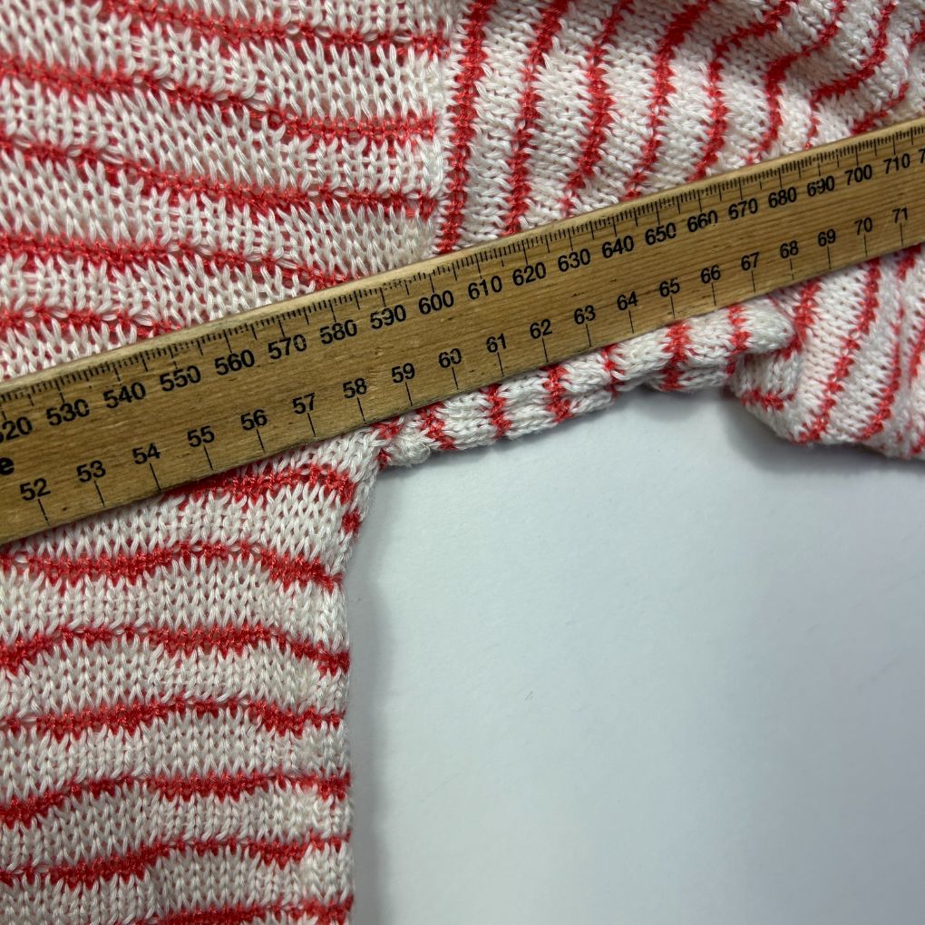 Red and white striped knit sleeve detail view with measuring tape