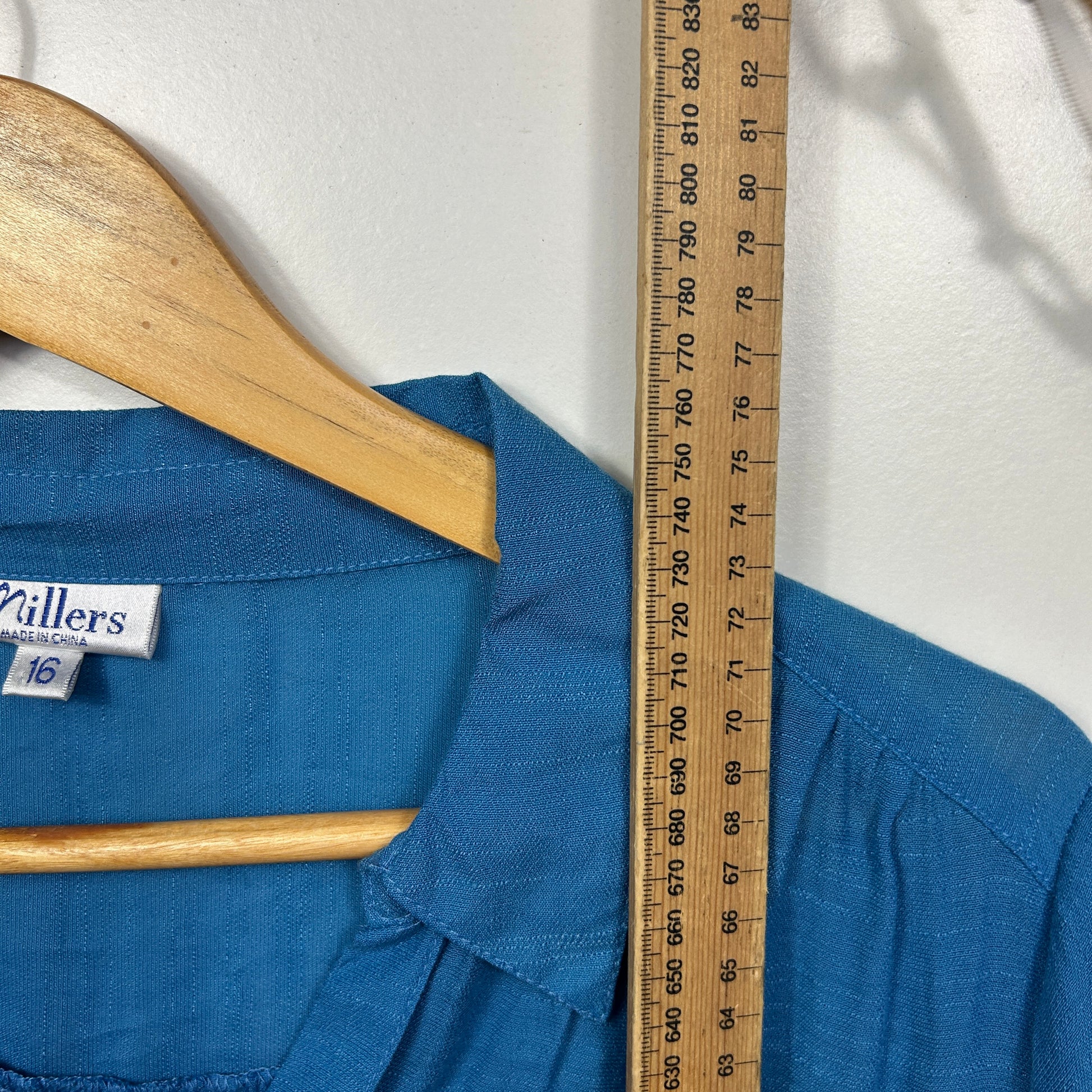 Blue shirt front view on wooden hanger with measuring tape