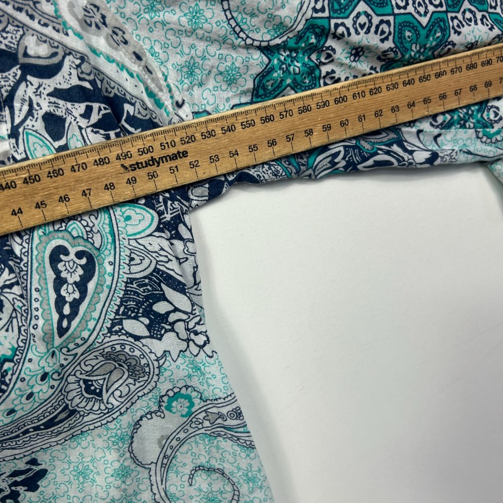 Teal and navy paisley patterned fabric with measuring tape detail view