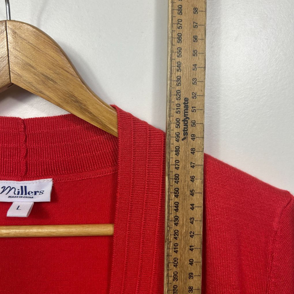 Red ribbed jumper front view with wooden hanger and measuring tape