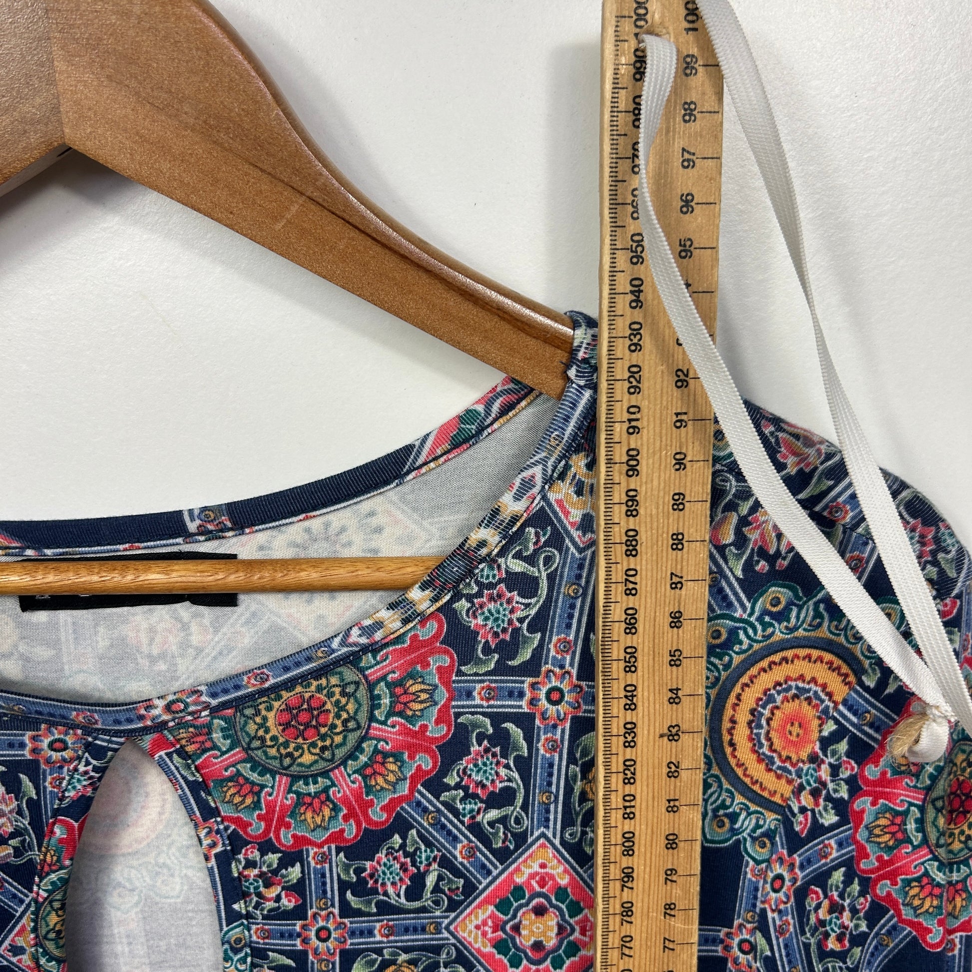 Navy floral patterned tank top detail view with wooden hanger and measuring tape