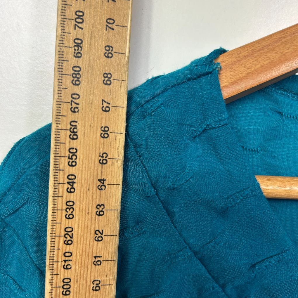 Teal jacket detail view with wooden ruler