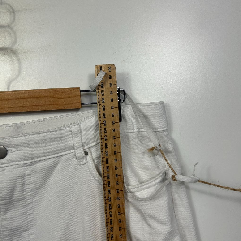 White pants waistband detail view with measuring tape