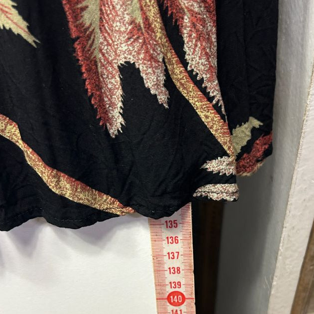 Black garment with gold and red embroidered details, measuring tape detail view
