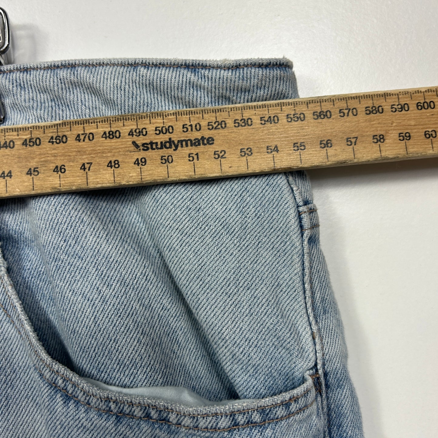 Light blue striped jeans detail view with measuring tape