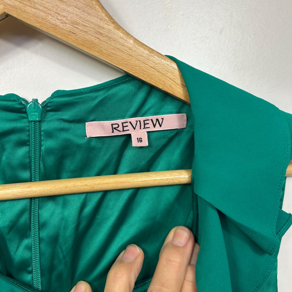 Green jacket detail view on wooden hanger