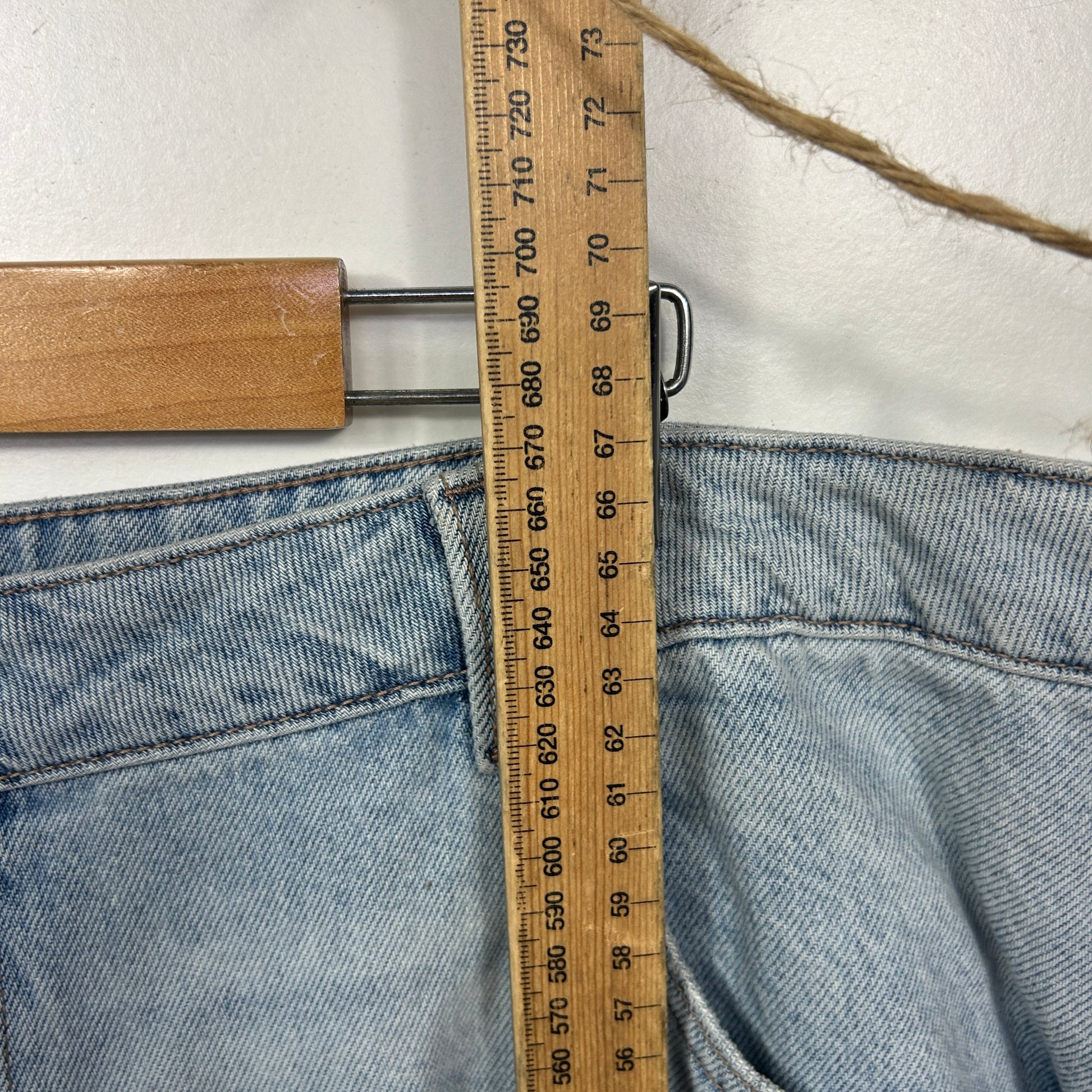 Light blue denim jeans with measuring tape detail view