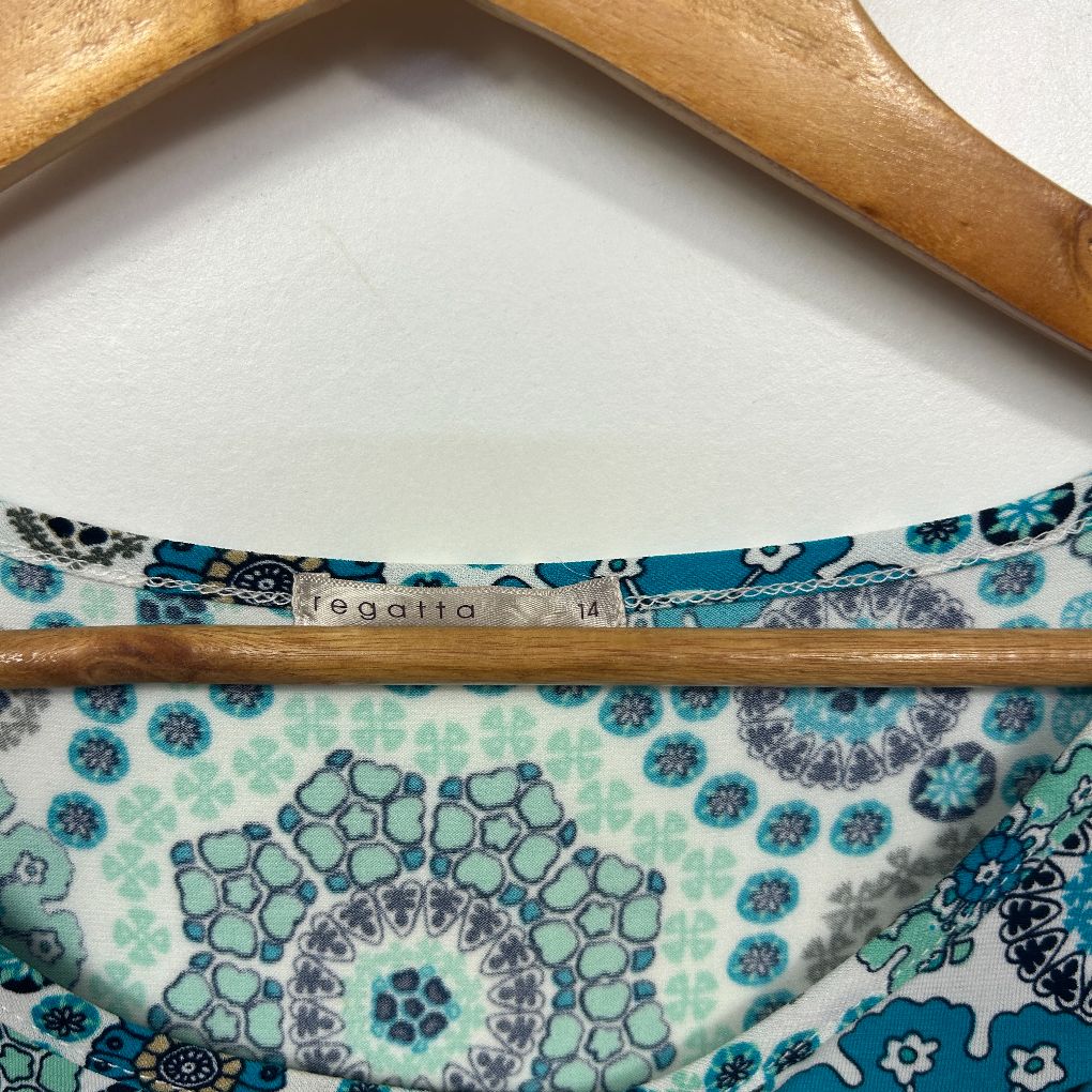 Blue floral dress detail view showing fabric pattern and wooden hanger