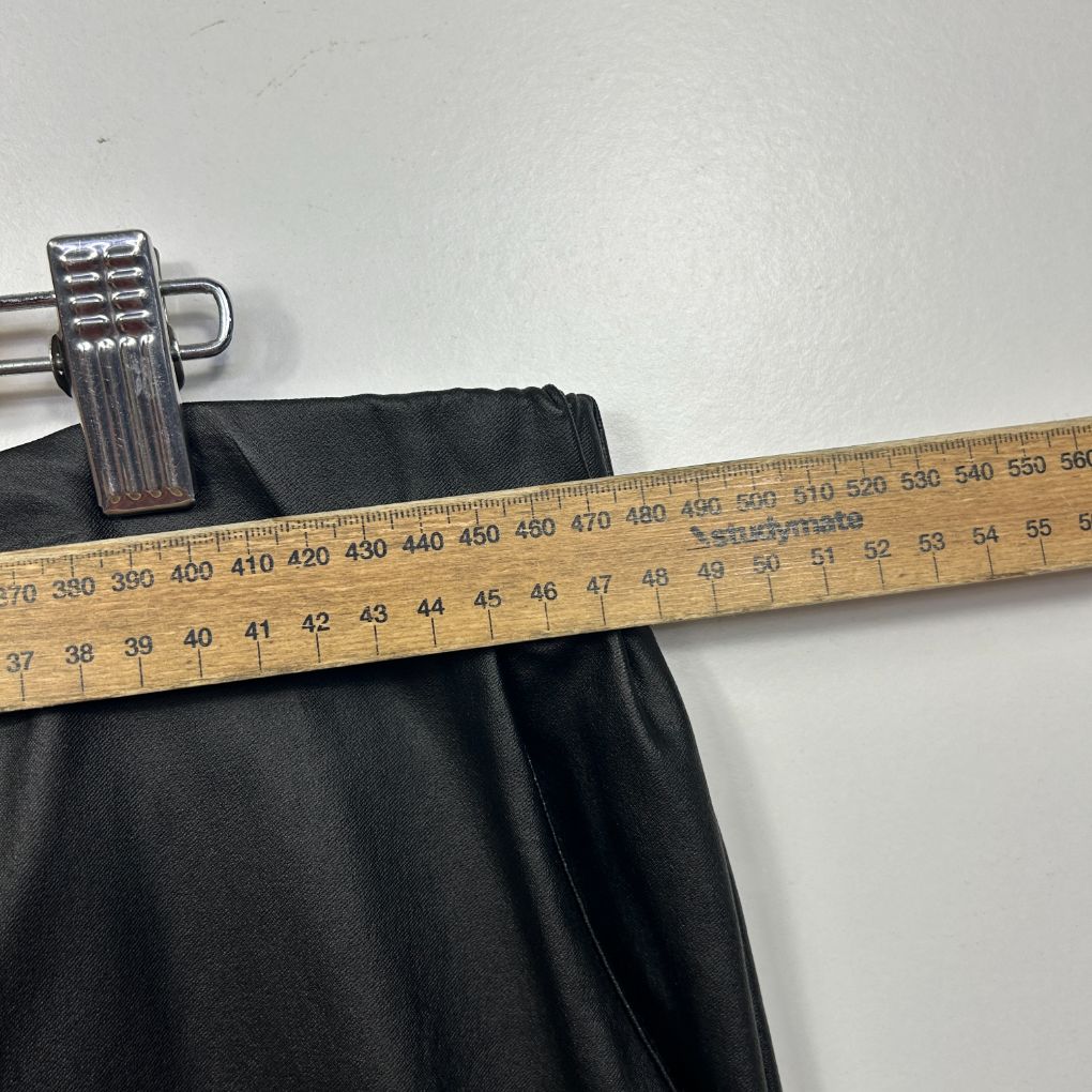 Black pants waistband detail view with measuring tape