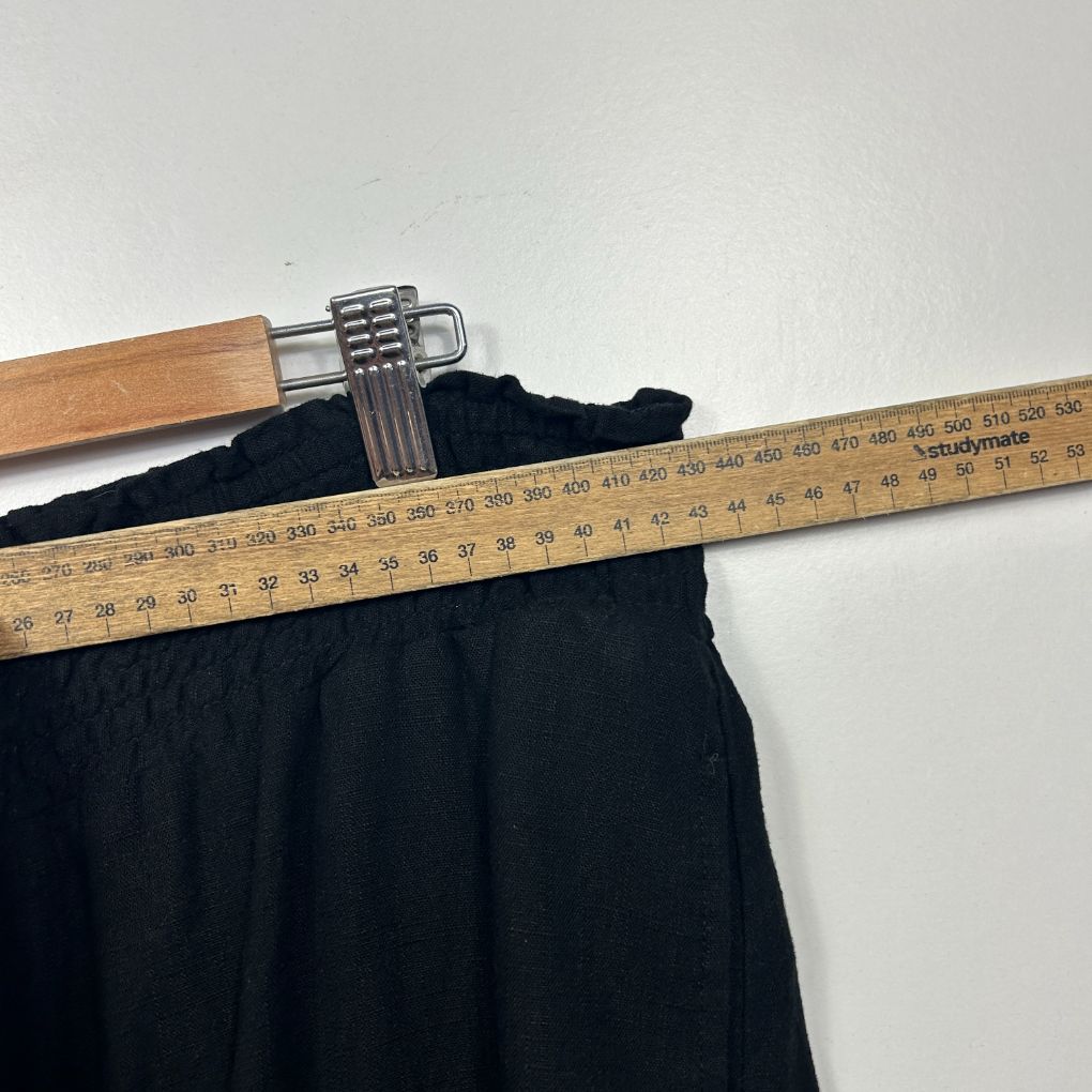Black pants waistband detail view with measuring tape