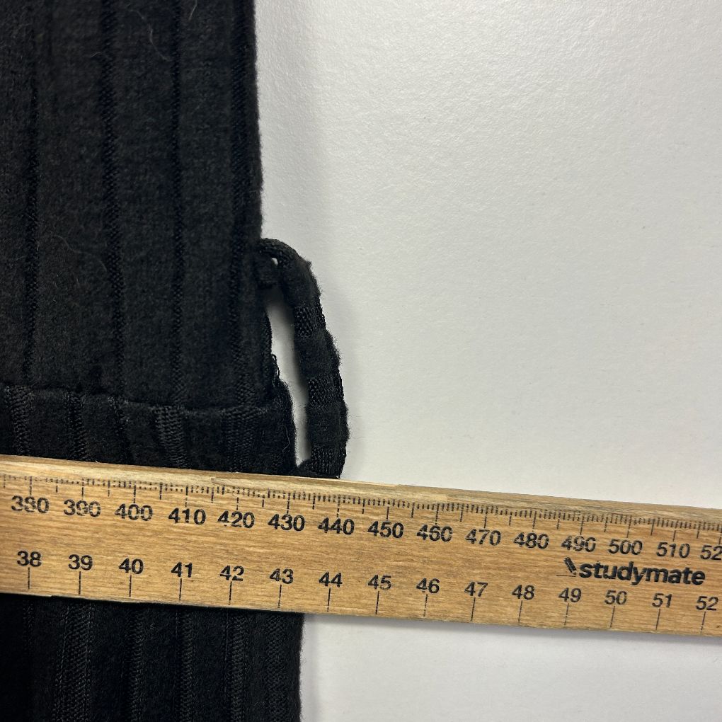 Black garment detail view with measuring tape