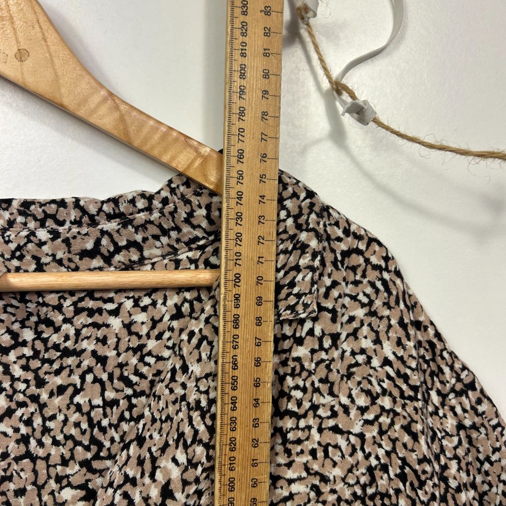 Black and cream patterned top front view with wooden hanger and measuring tape