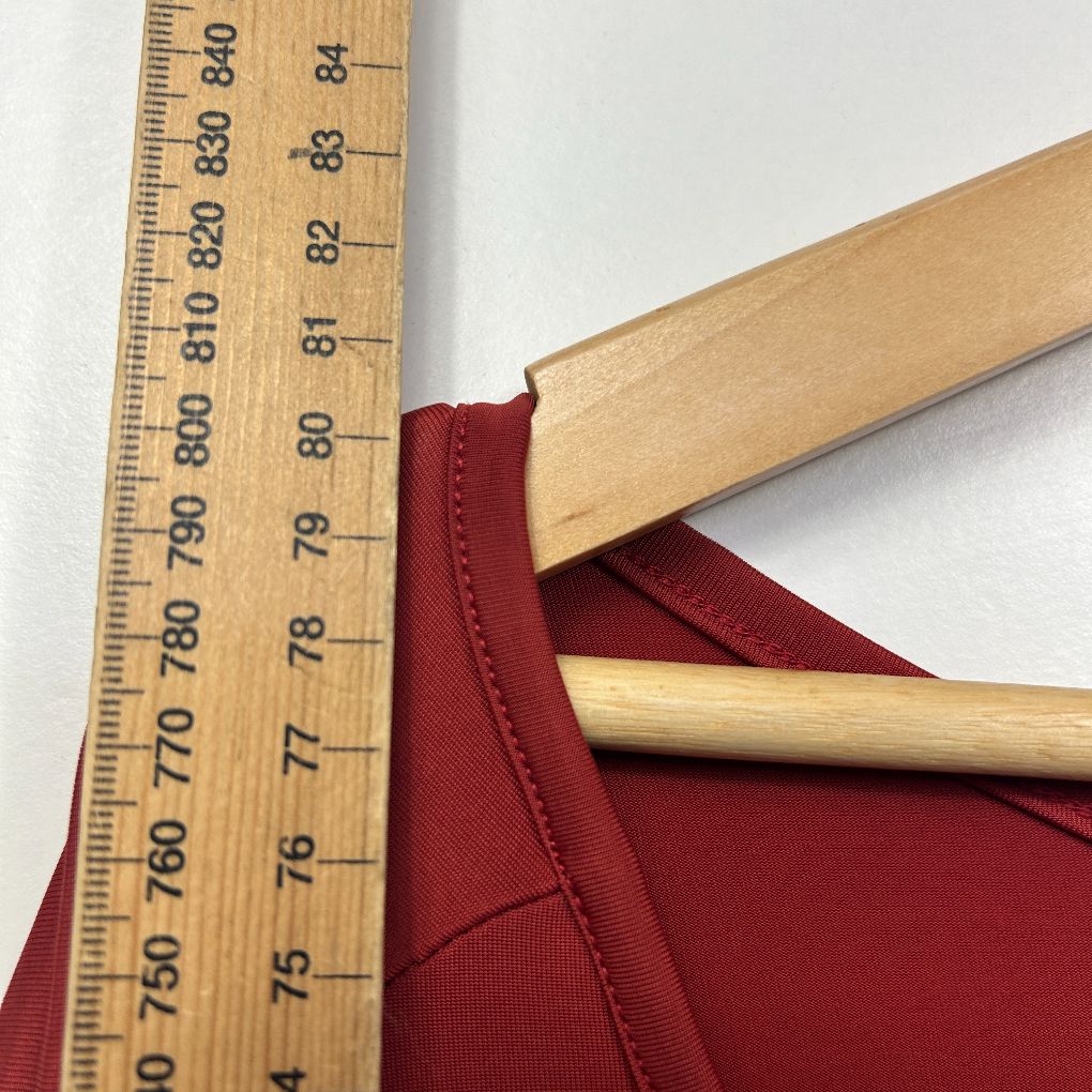 Burgundy garment detail view with wooden hanger and measurement ruler