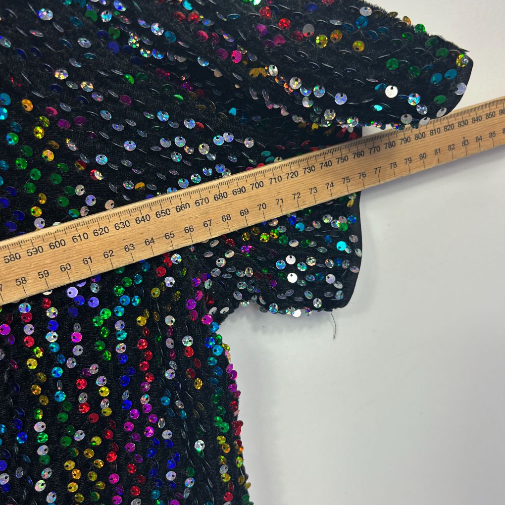 Black sequin fabric detail view with colorful multicolored sequins and measurement ruler