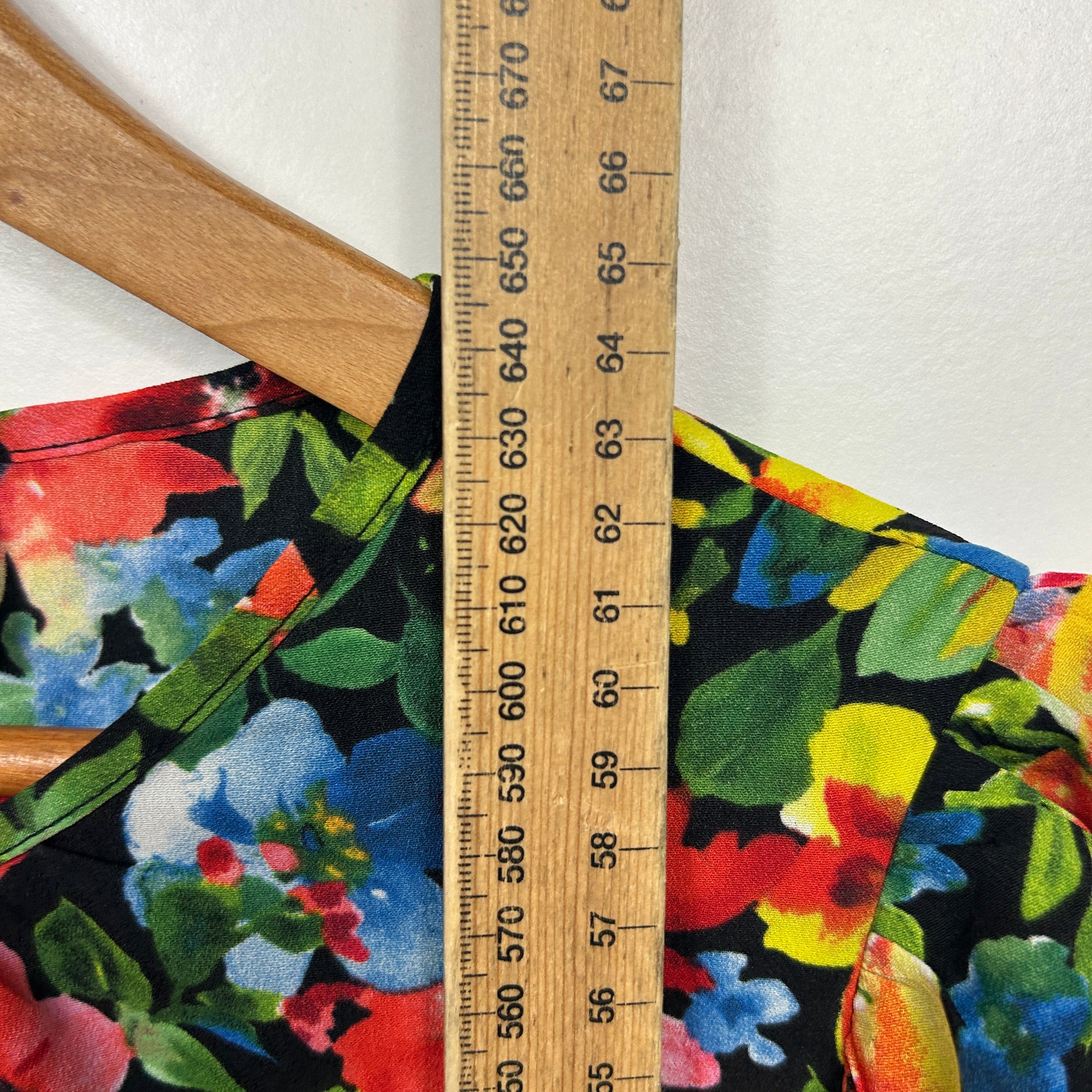 Colorful floral shirt detail view with wooden hanger and measuring ruler