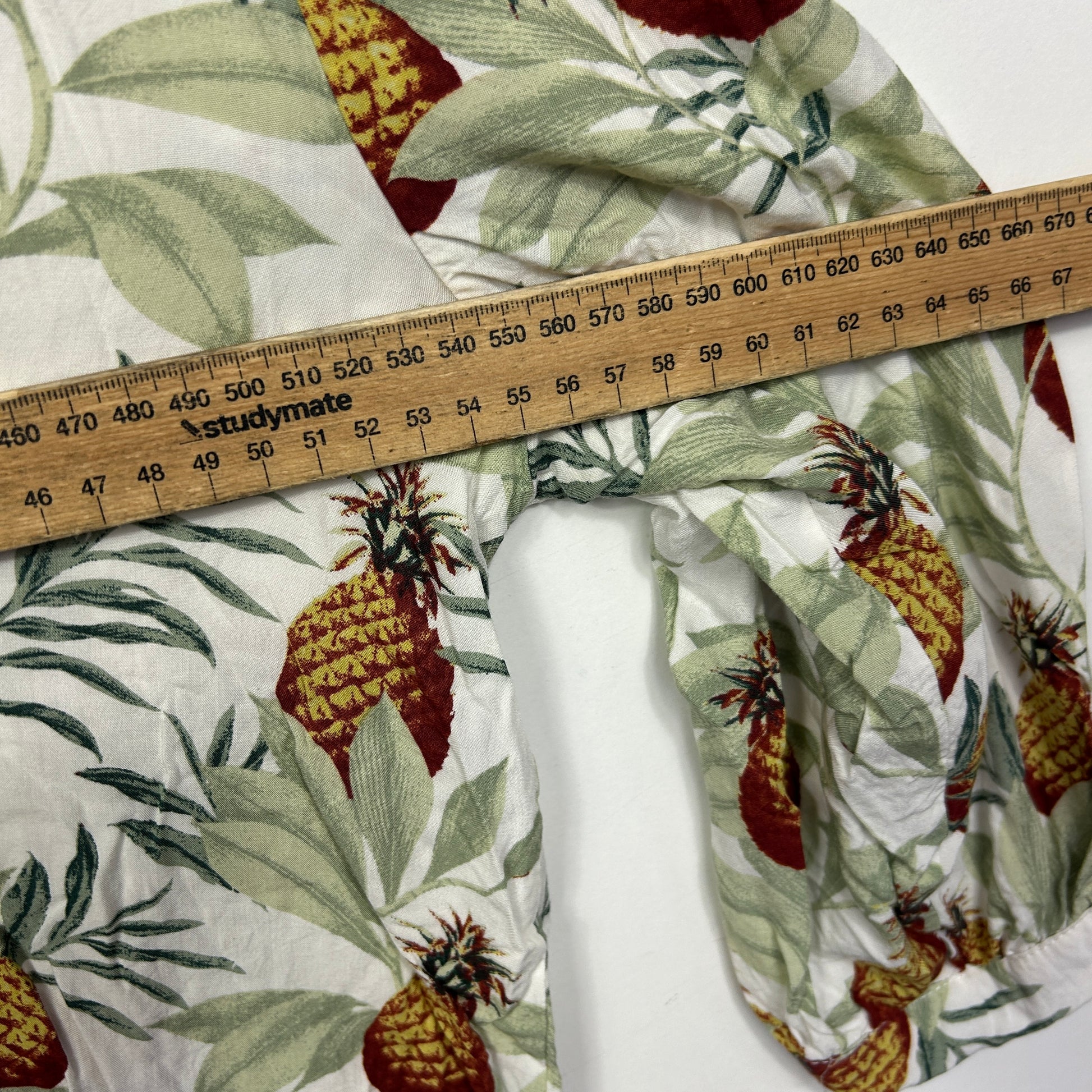 Cream fabric with pineapple and leaf print detail view with measuring tape