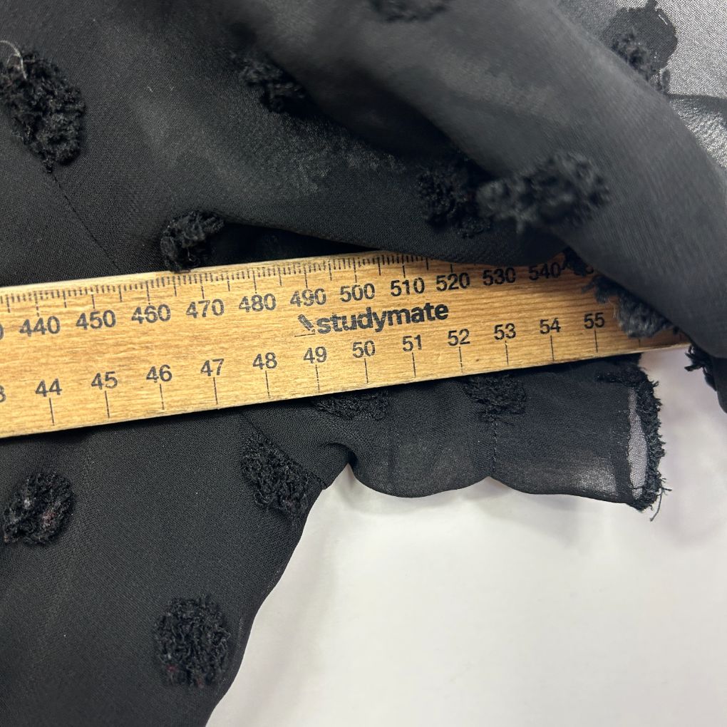 Black fabric with floral pattern detail view with measuring ruler
