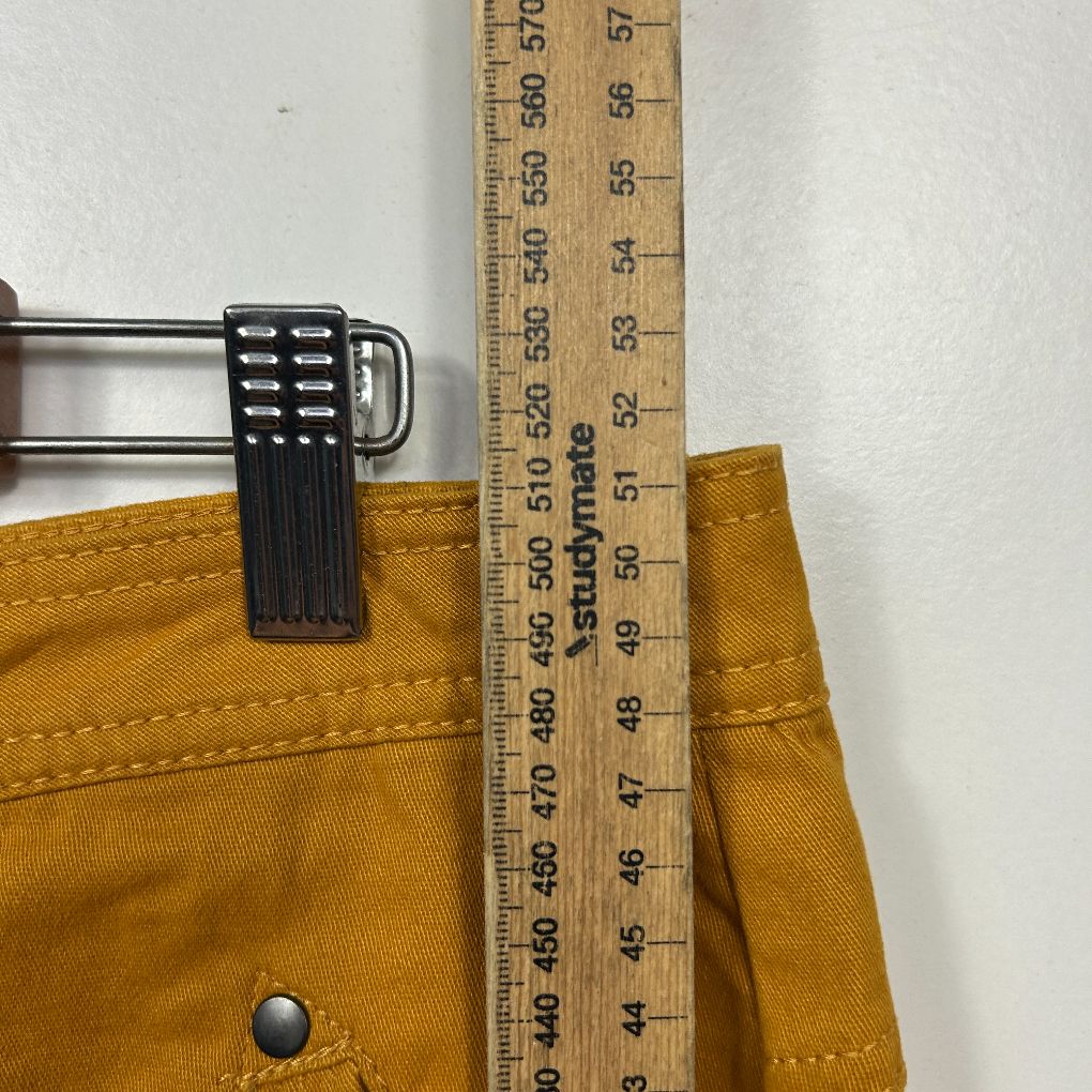 Mustard yellow pants waistband detail view with measuring tape