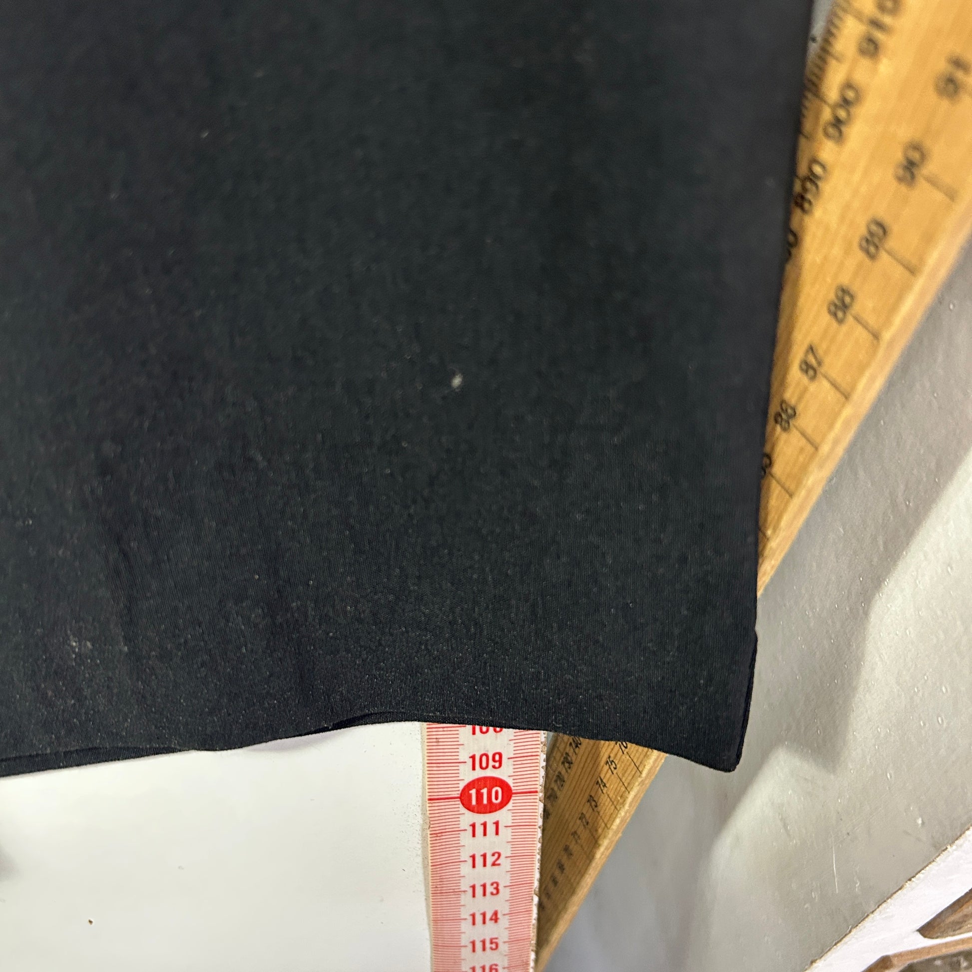 Black garment front view with measuring tape