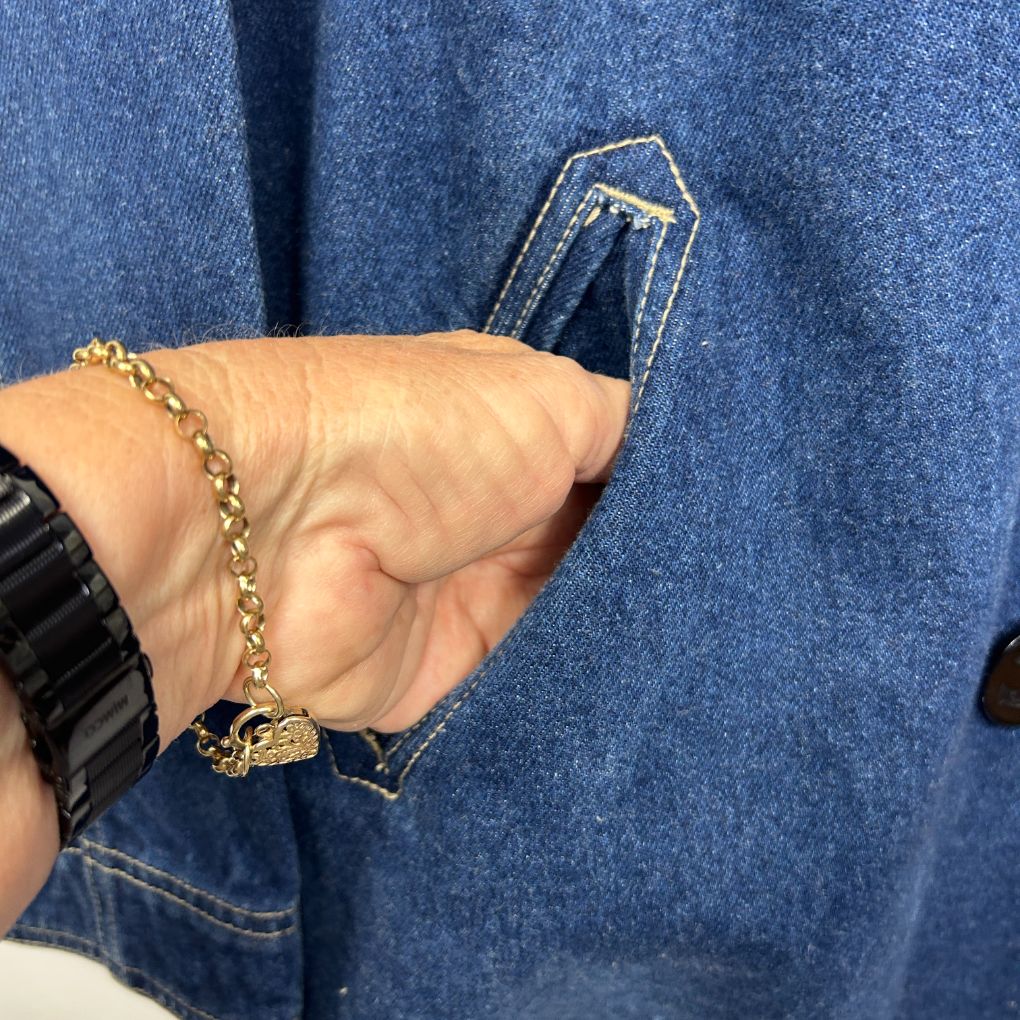 Blue denim jacket detail view with chain bracelet