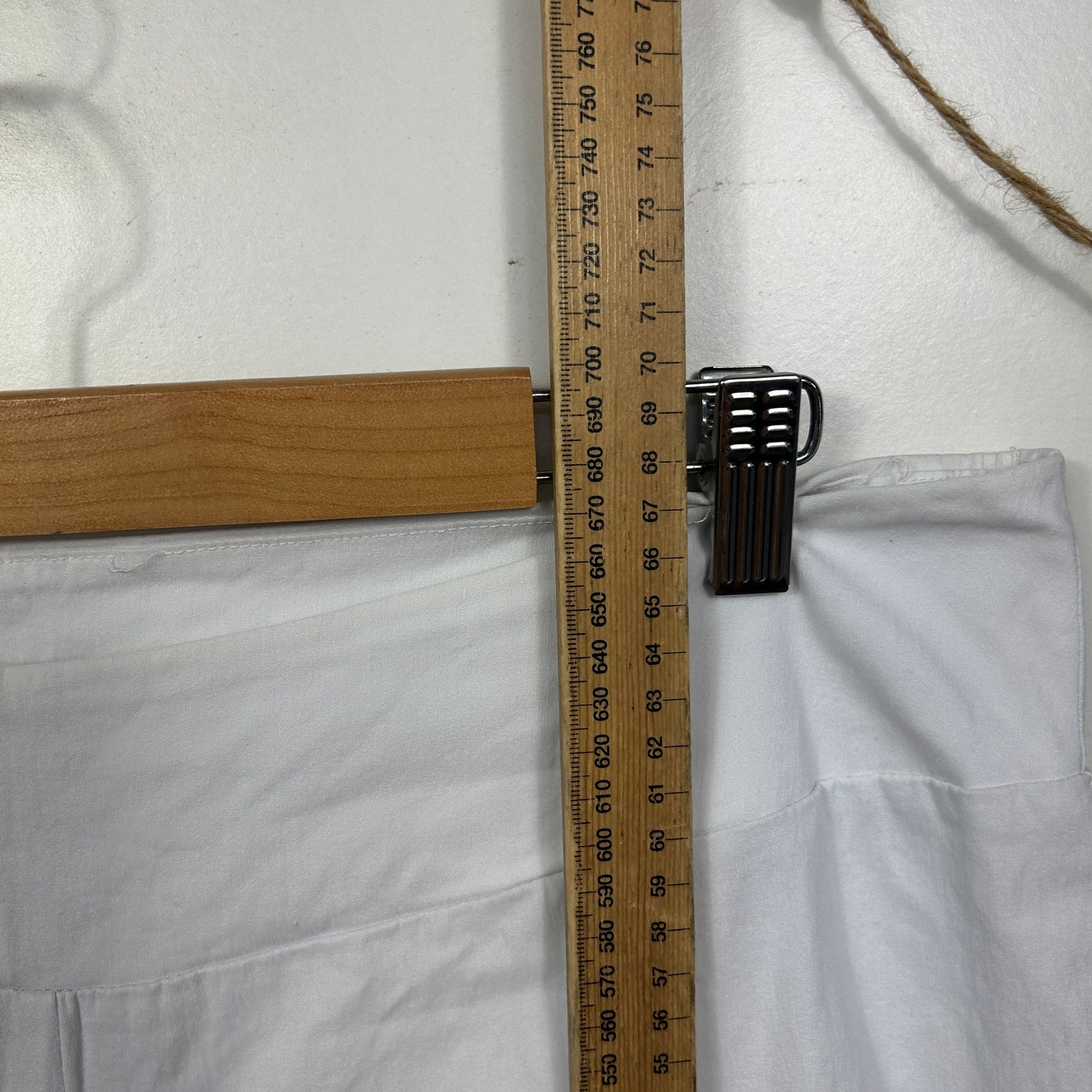 White fabric detail view with wooden ruler and black clip measurement