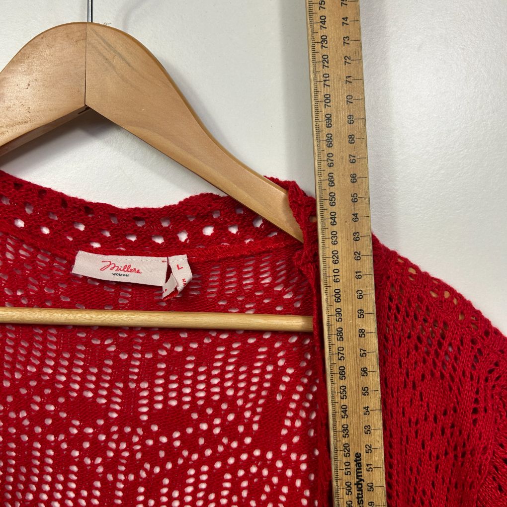 Red knit sweater detail view with measuring tape