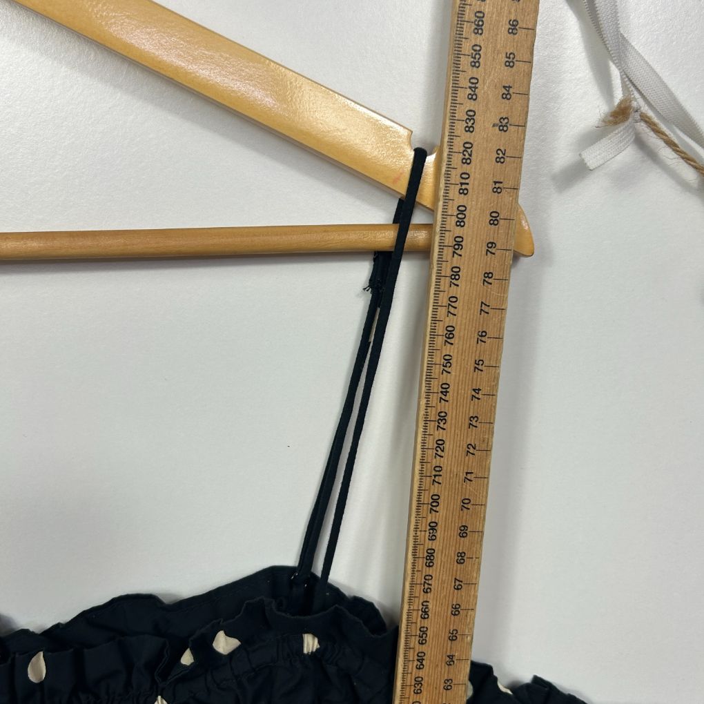 Black knit garment detail view with wooden measuring tools