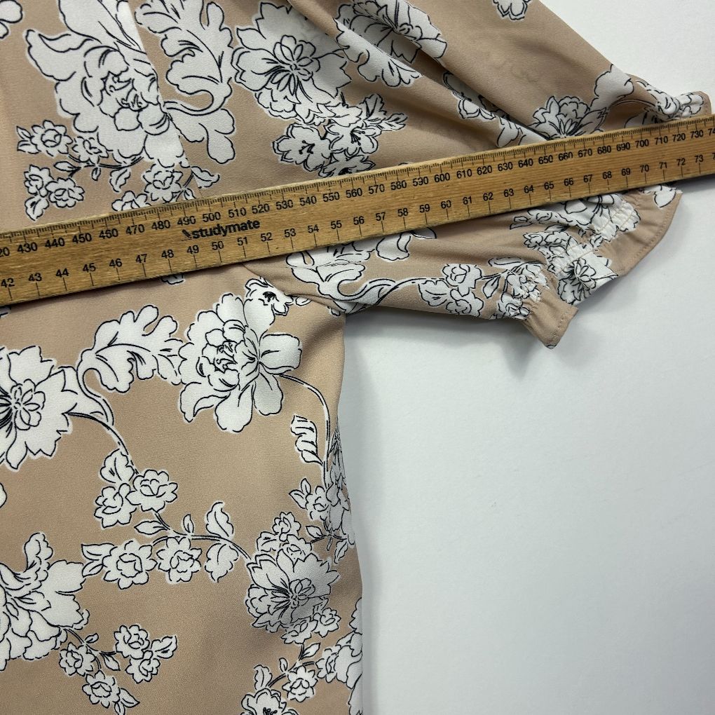 Beige fabric with white floral print detail view with measuring tape