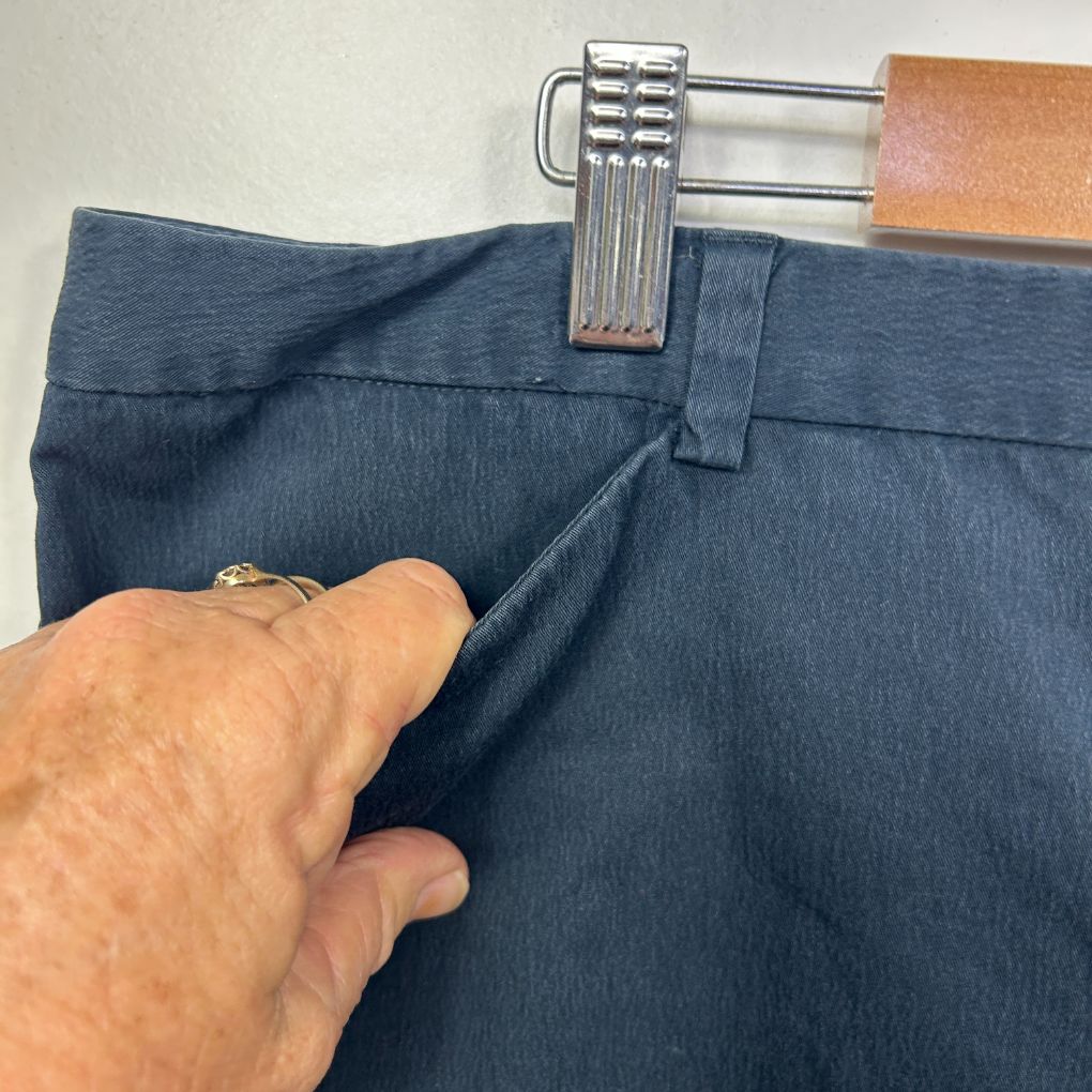 Blue denim jeans front view with hand holding waistband