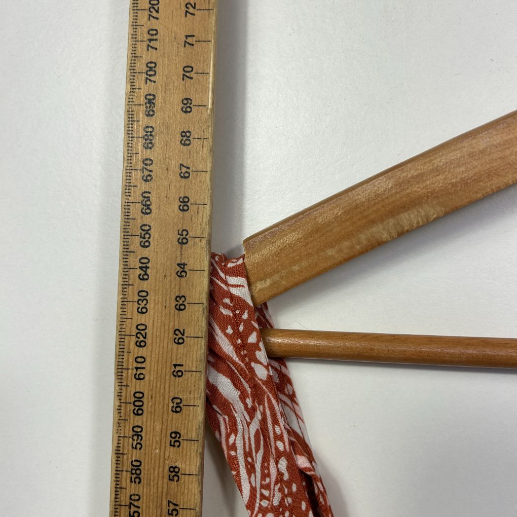 Red and white patterned fabric detail view with wooden hanger
