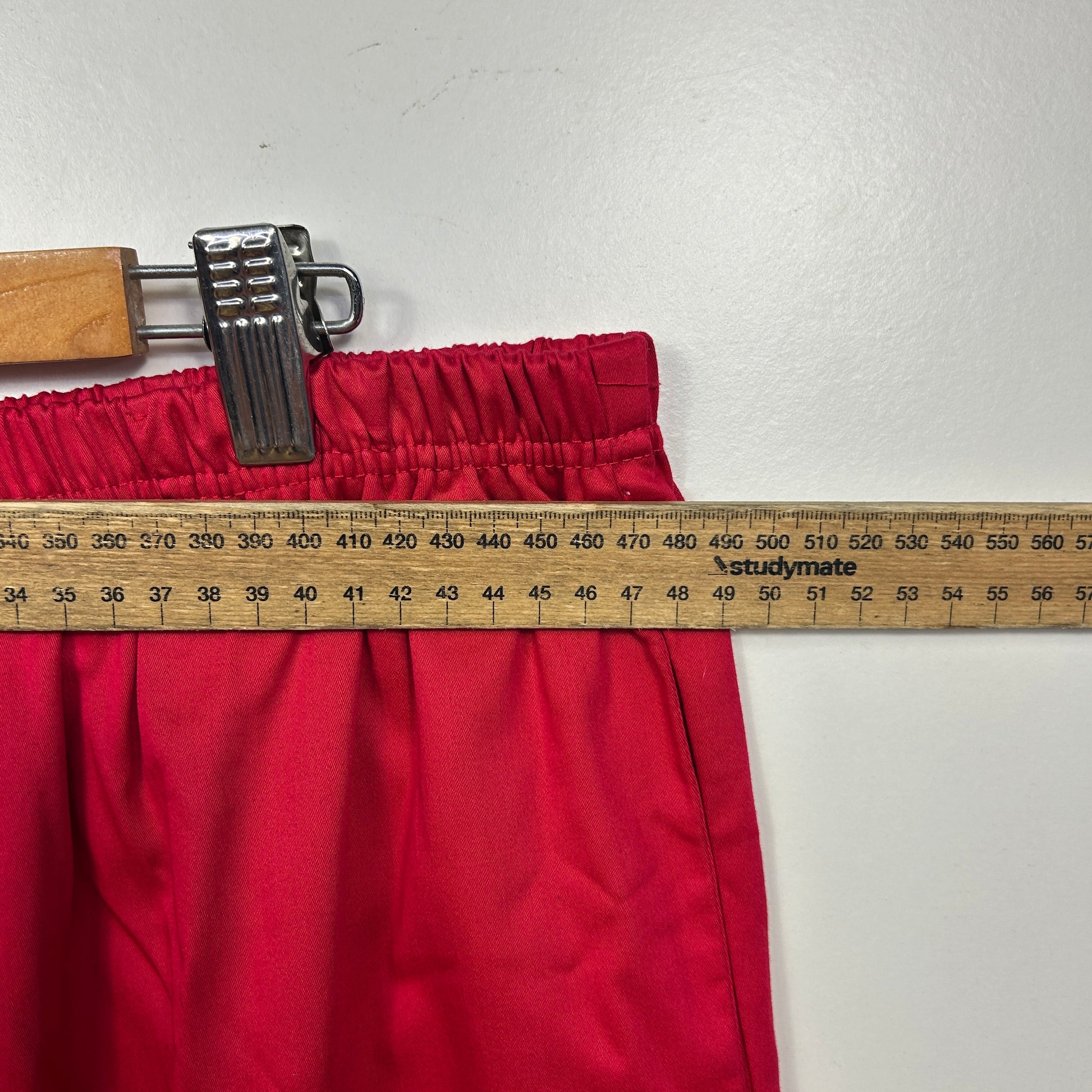 Red pants waistband detail view with measuring tape