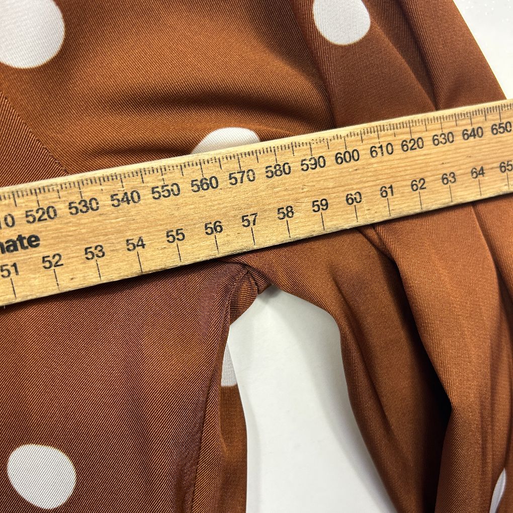 Brown polka dot fabric with measuring tape detail view