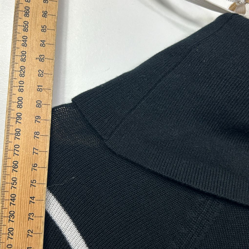 Black ribbed knit fabric detail view with measuring tape
