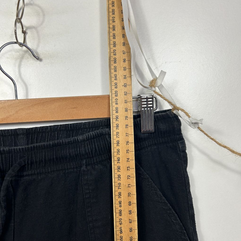 Dark navy pants on wooden hanger with measuring tape detail view
