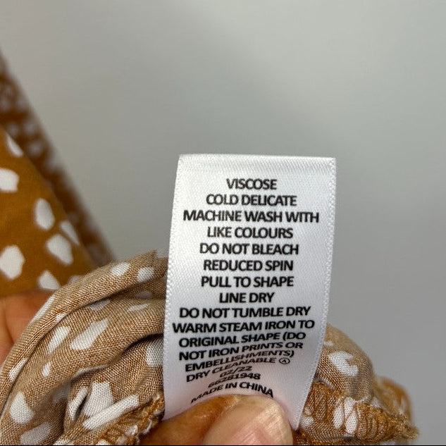 Brown and white polka dot fabric care label detail view