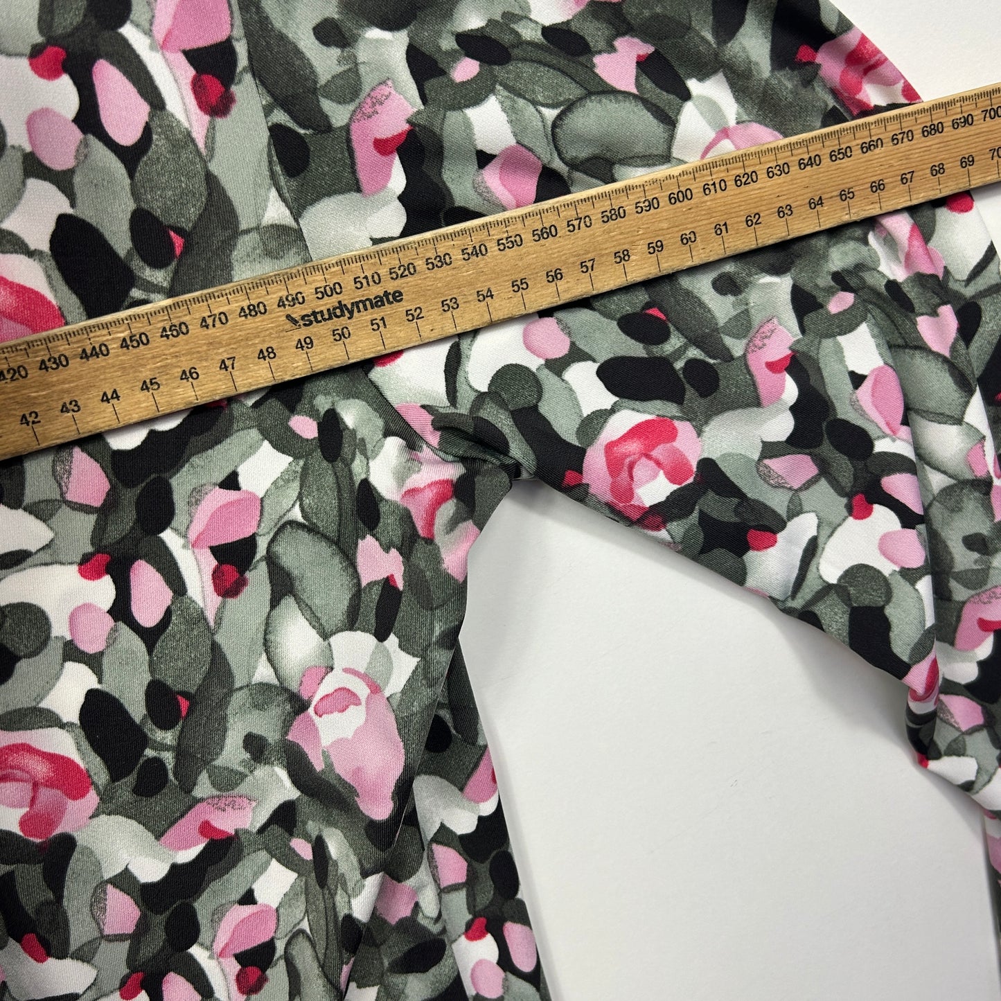 Pink and black floral print fabric detail view with measuring tape