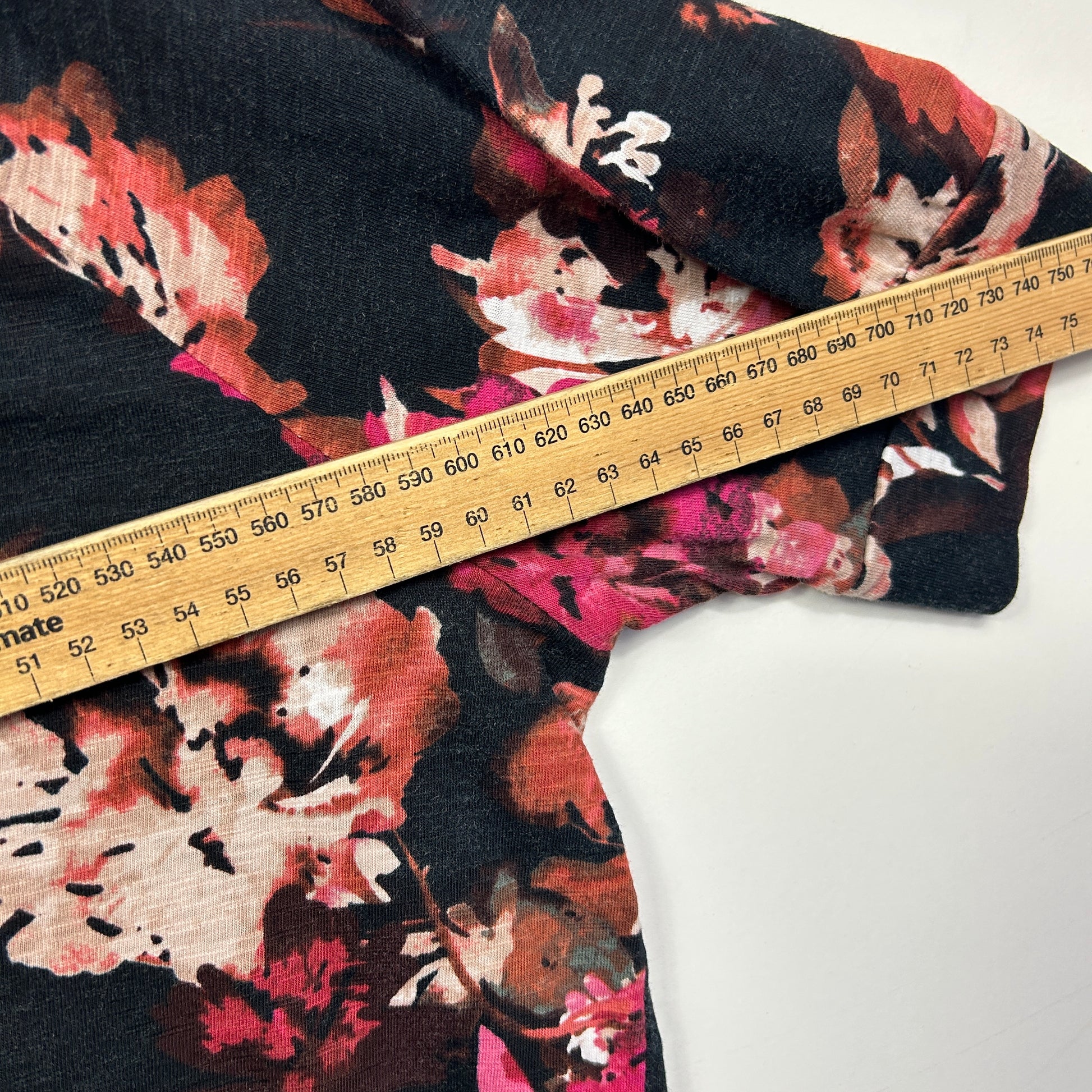 Black floral sweater detail view with measuring tape