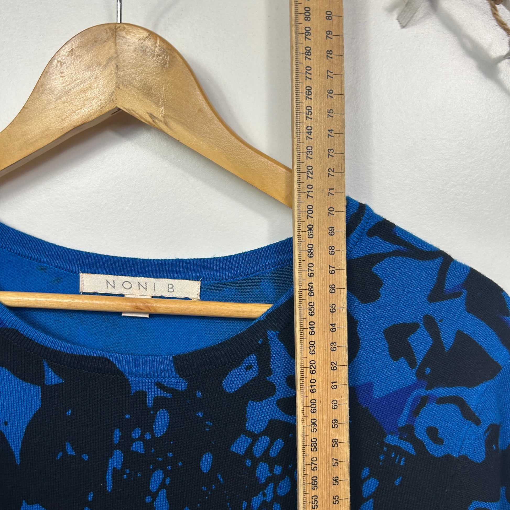 Blue and black graphic sweater detail view with wooden hanger