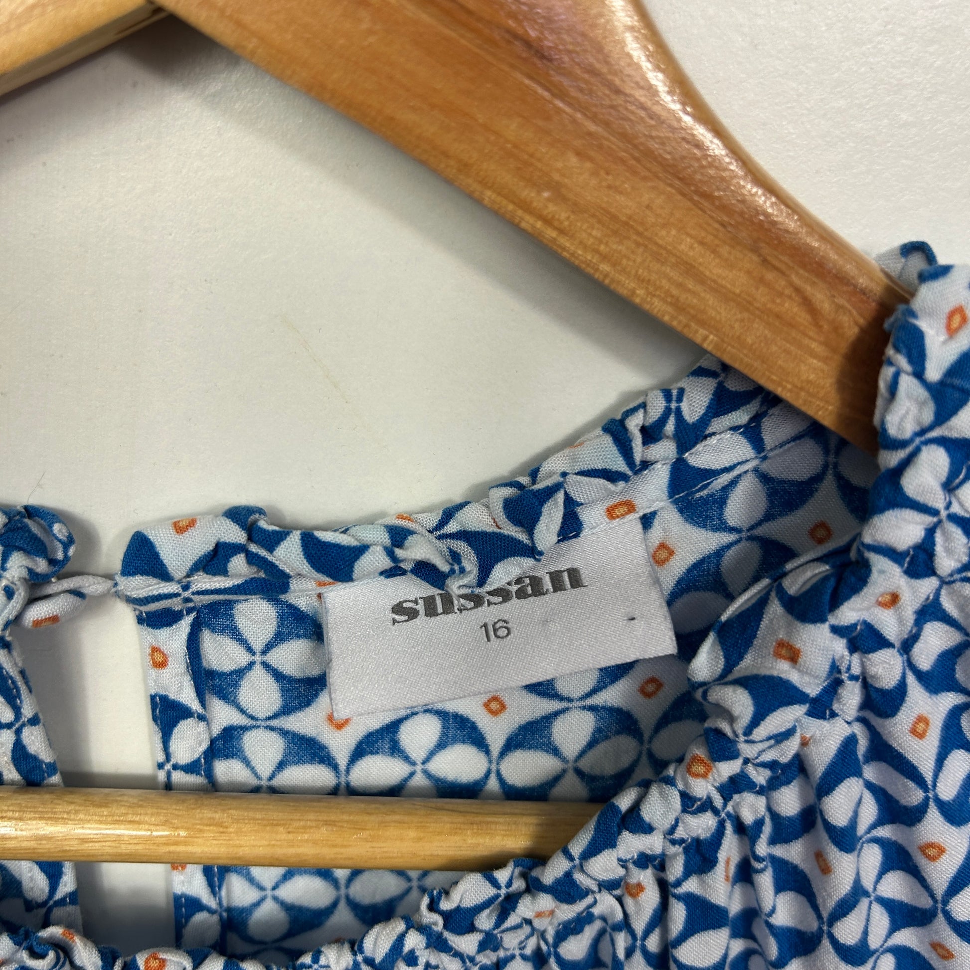 Blue and white floral dress detail view showing label and wooden hanger