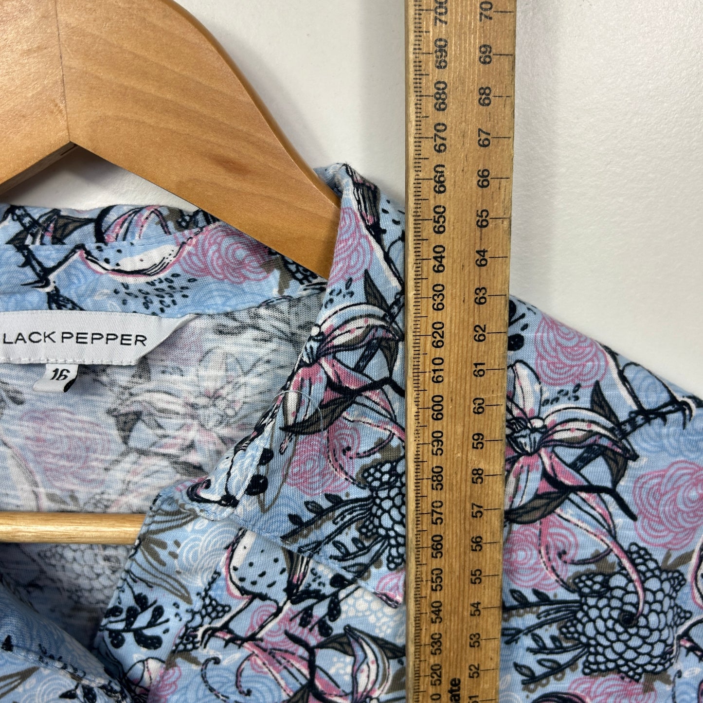 Blue and purple graphic patterned top front view on hanger with measurement scale