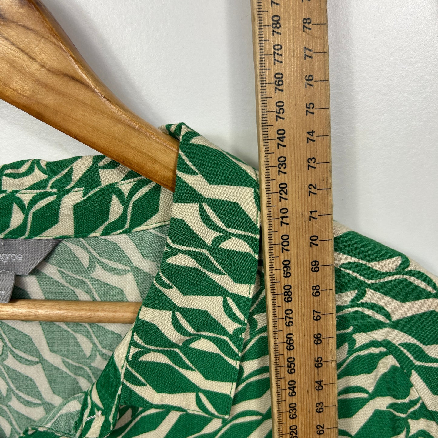 Green and cream leaf patterned fabric detail view with wooden handles and measuring tape