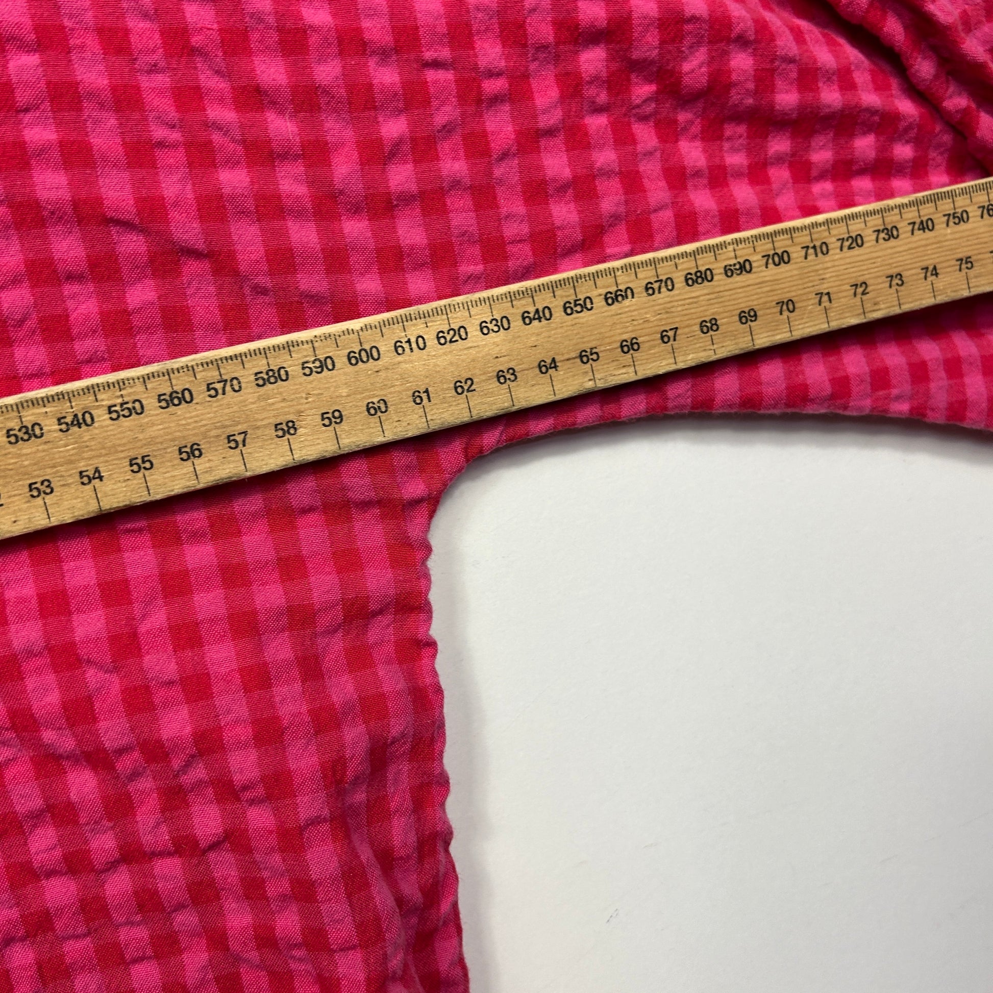 Pink checkered fabric detail view with measuring tape