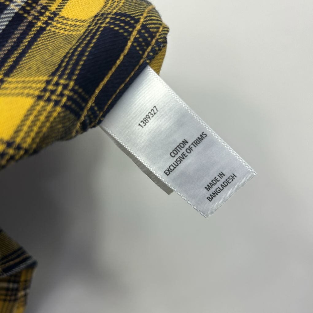 Yellow and navy plaid fabric detail view with clothing label